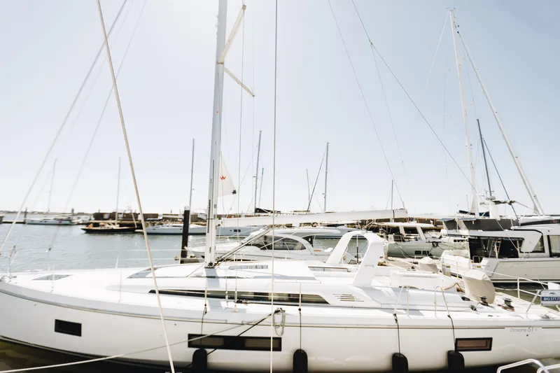 Slide: The Image of 2024 Beneteau Oceanis 51.1 sailboat docked in a sunny marina. - 1