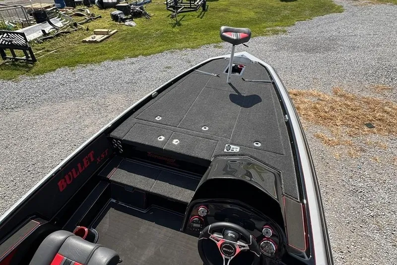 Slide: The Image of 2026 Bullet 21XST boat interior with steering wheel and seating, parked on gravel. - 7