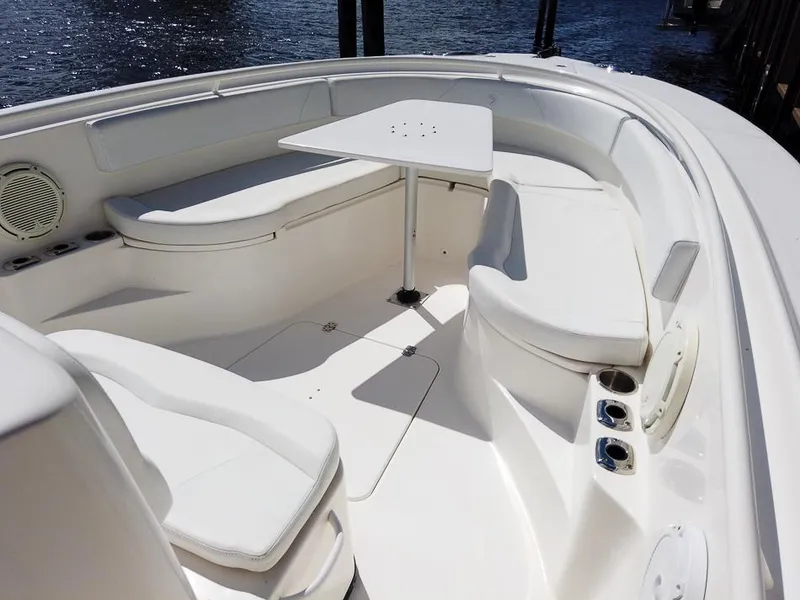 Slide: The Image of 2015 Edgewater 320CC boat interior with white seating and table, docked by the water. - 13