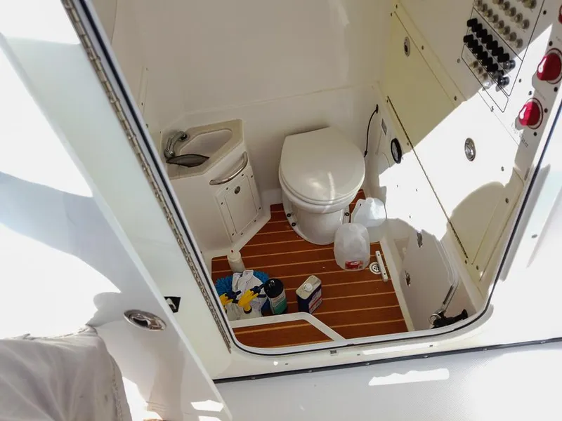 Slide: The Image of Interior of 2015 Edgewater 320CC boat bathroom with toilet, sink, and cleaning supplies. - 15