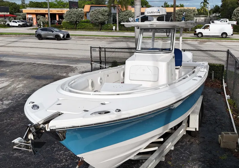 Slide: The Image of 2015 Edgewater 320CC boat on trailer, parked near a road with vehicles. - 2