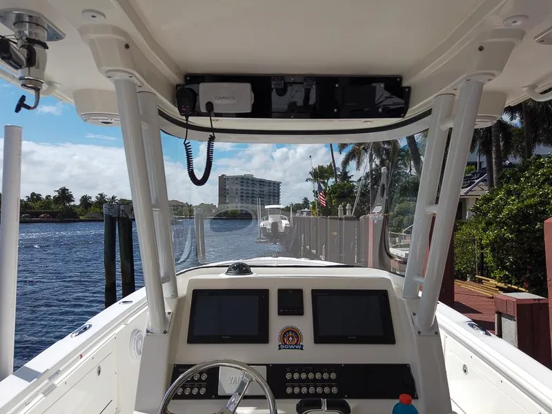 Slide: The Image of Edgewater 320CC boat dashboard view, navigating a sunny waterfront with palm trees. - 20