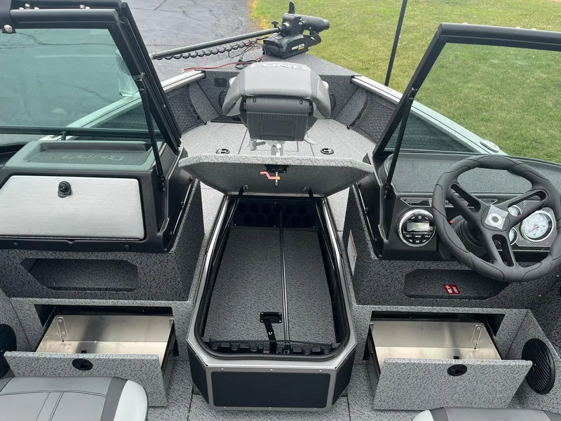Slide: The Image of 2026 Lund 1775 Impact XS Sport boat interior with open storage compartments and steering wheel. - 15
