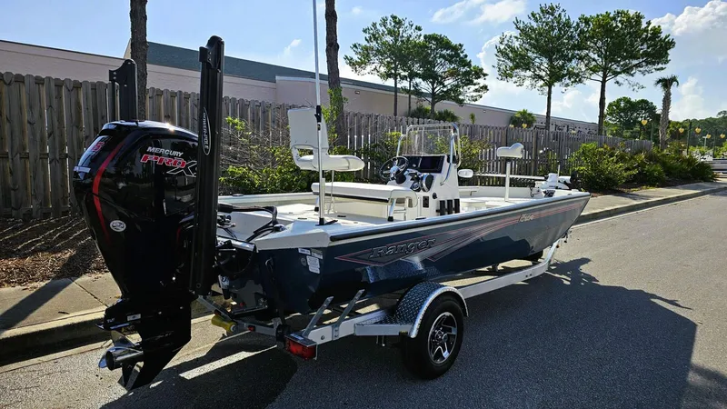Slide: The Image of 2025 Ranger RB190 boat with Mercury Pro XS engine on a trailer, parked outdoors. - 1