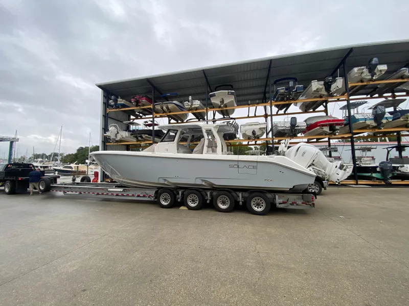 Slide: The Image of 2025 Solace 37 CS boat on trailer at marina with stacked boats in background. - 21