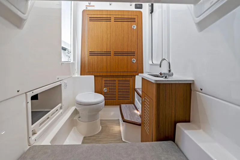 Slide: The Image of 2025 Solace 32 CS boat interior with wooden cabinetry, toilet, and sink. - 5