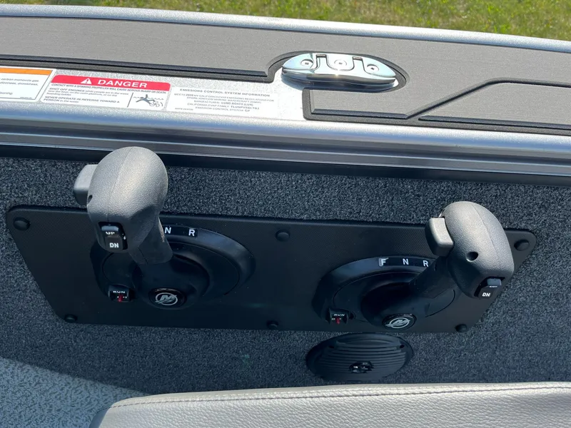 Slide: The Image of 2026 Lund 2075 Fisherman boat controls with dual levers and warning label. - 23