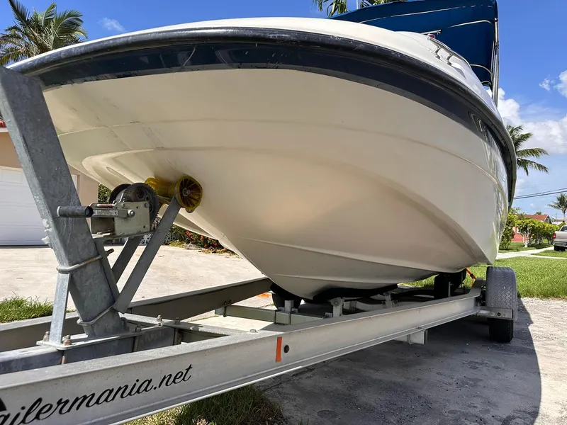 Slide: The Image of 2001 Bayliner 215 Deck Boat on trailer, parked outdoors under clear blue sky. - 10