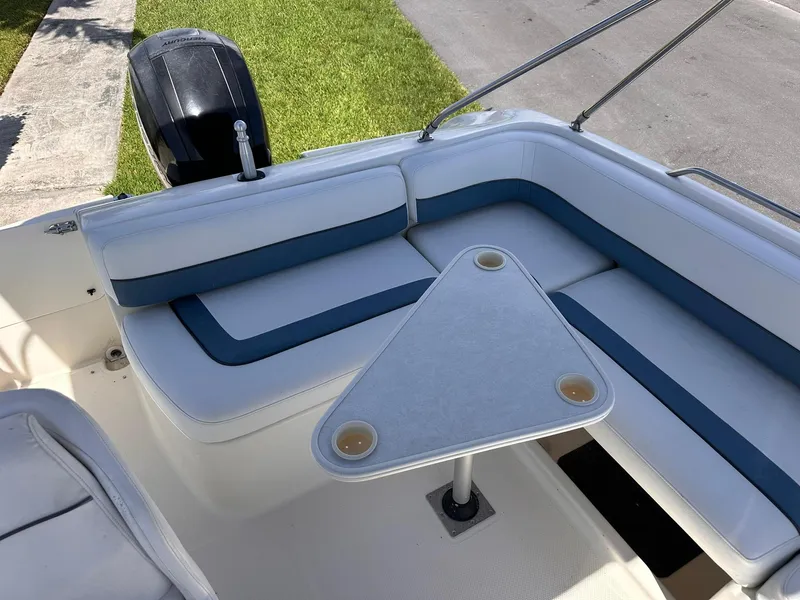 Slide: The Image of 2001 Bayliner 215 Deck Boat interior with cushioned seating and triangular table. - 12