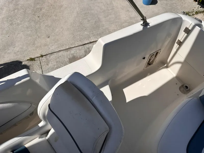 Slide: The Image of 2001 Bayliner 215 Deck Boat interior with white seating and storage compartment. - 15