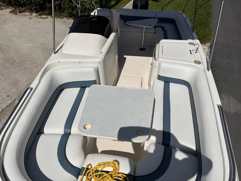 Slide: The Image of 2001 Bayliner 215 Deck Boat interior with seating and table, docked on a sunny day. - 20