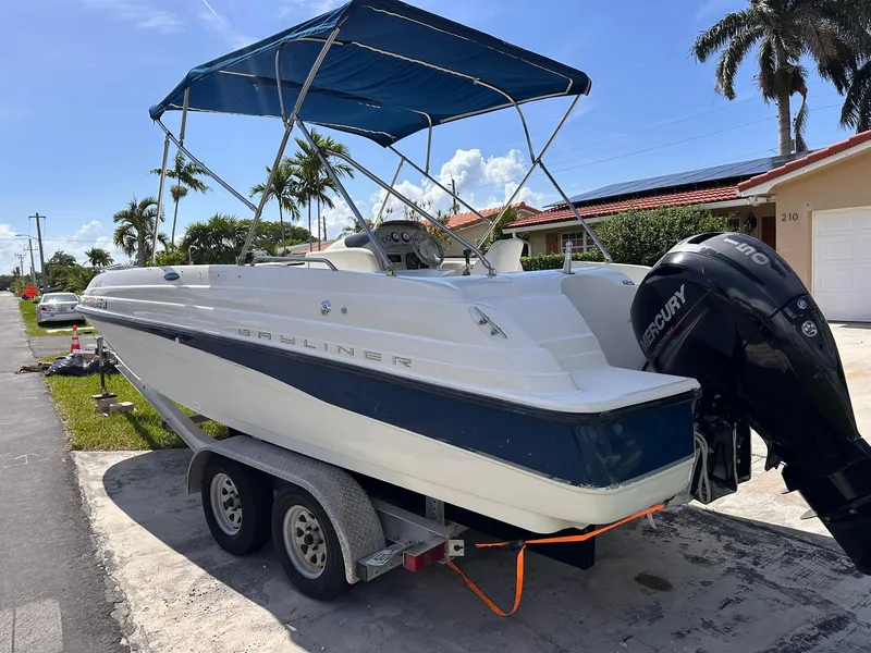 Slide: The Image of 2001 Bayliner 215 Deck Boat on trailer with Mercury outboard motor, parked in driveway. - 3