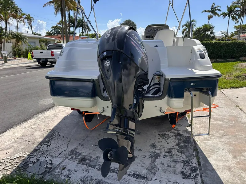Slide: The Image of 2001 Bayliner 215 Deck Boat with outboard motor, parked on a sunny street. - 4