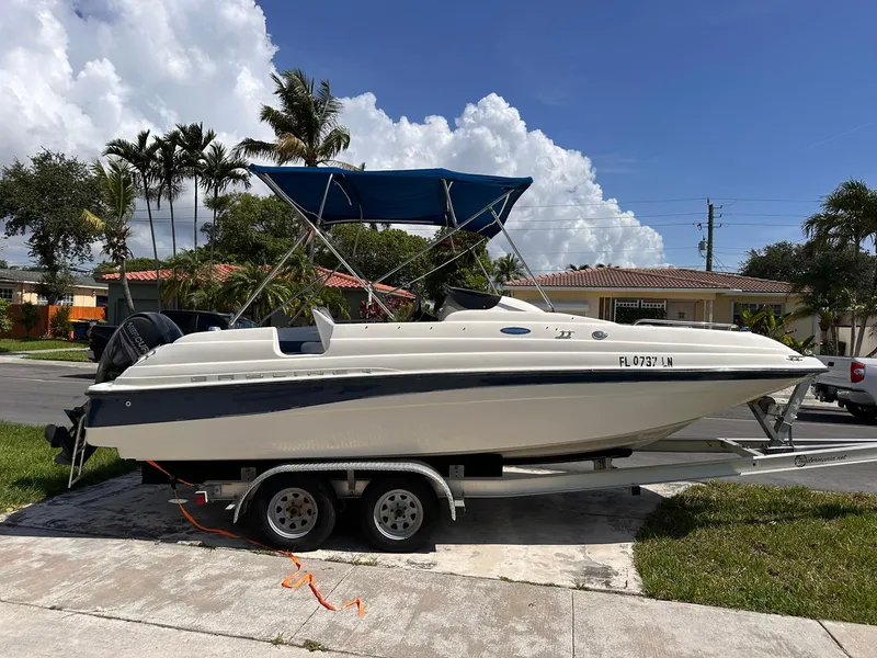 Slide: The Image of 2001 Bayliner 215 Deck Boat on trailer, parked in a suburban neighborhood. - 7