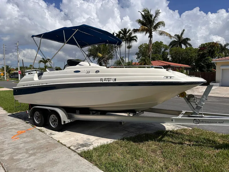 Slide: The Image of 2001 Bayliner 215 Deck Boat on trailer, parked in a suburban neighborhood. - 8