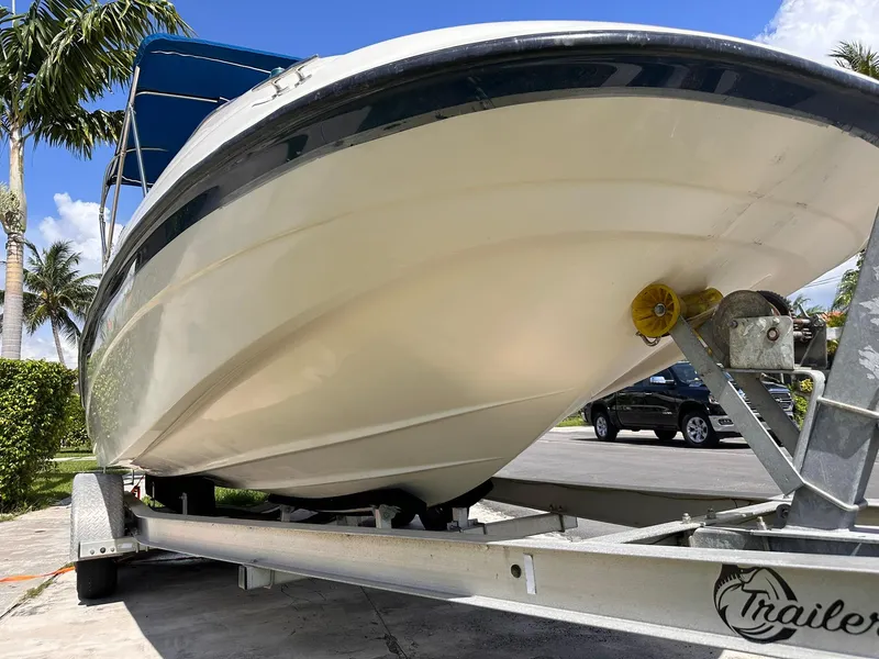 Slide: The Image of 2001 Bayliner 215 Deck Boat on trailer, parked outdoors under clear blue sky. - 9
