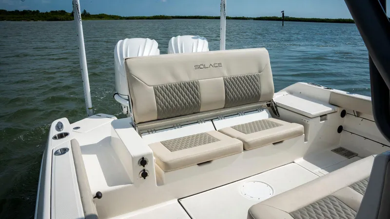 Slide: The Image of 2025 Solace 28 HCS boat interior with cushioned seating on calm water. - 7