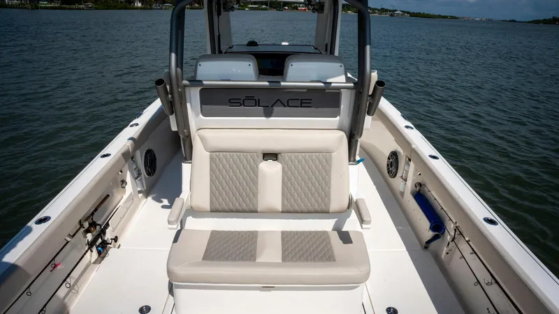 Slide: The Image of 2025 Solace 28 HCS boat interior with cushioned seating on calm water. - 9