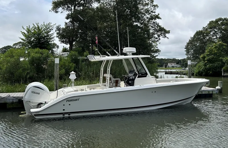Slide: The Image of 2026 Pursuit S 288 boat docked on a calm river with lush greenery. - 2