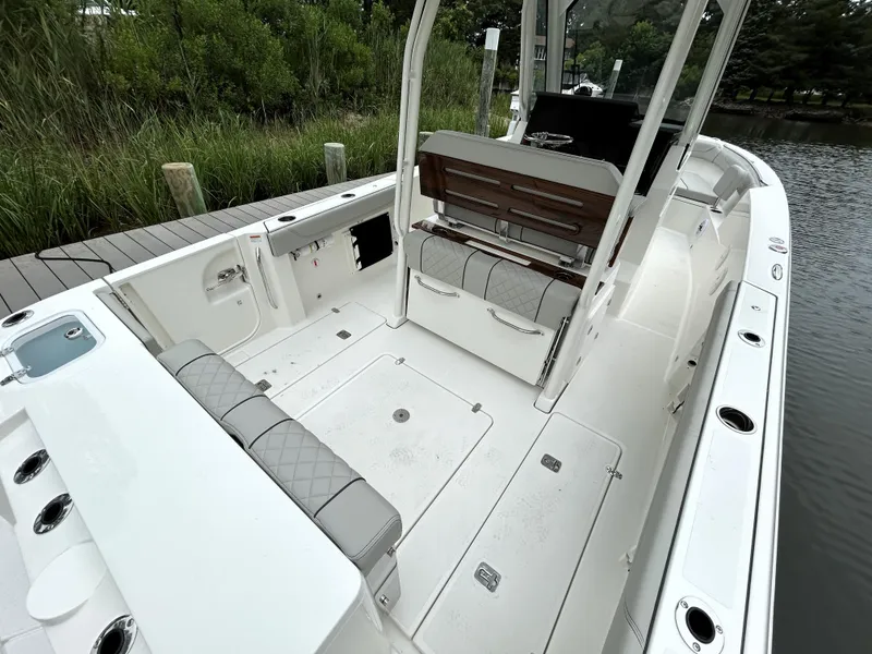 Slide: The Image of 2026 Pursuit S 288 boat interior with seating and storage, docked by lush greenery. - 7