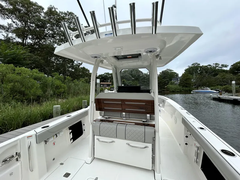 Slide: The Image of 2026 Pursuit S 288 boat interior with seating and rod holders, docked by lush greenery. - 9
