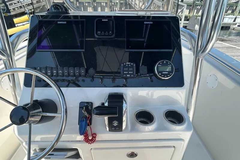 Slide: The Image of 2024 Bulls Bay 230 CC boat dashboard with steering wheel, controls, and Simrad displays. - 4