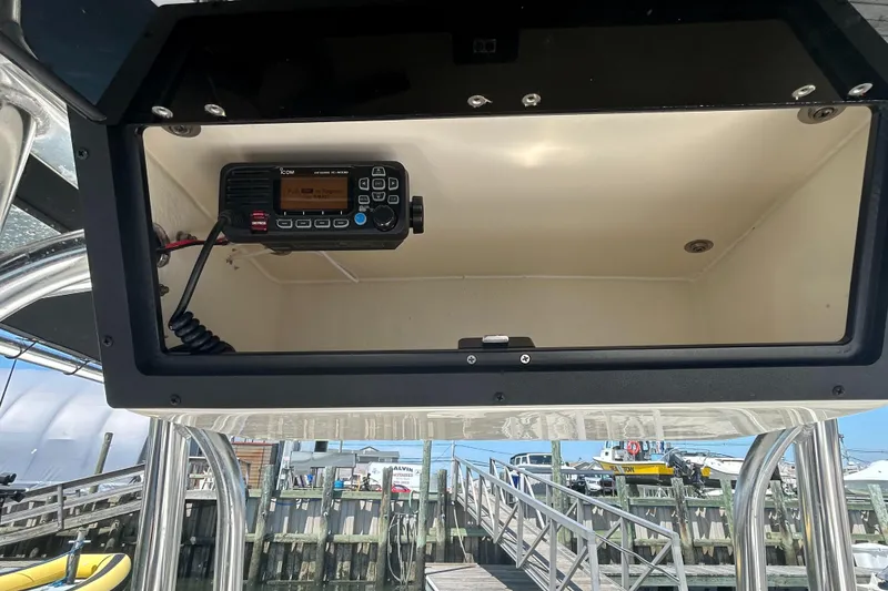 Slide: The Image of 2024 Bulls Bay 230 CC boat console with mounted radio, dockside view. - 7