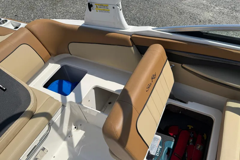 Slide: The Image of 2014 Sea Ray 240 Sundeck Outboard interior with tan seating and storage compartments. - 10