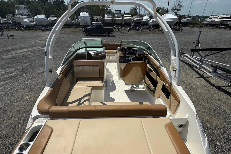 Slide: The Image of 2014 Sea Ray 240 Sundeck Outboard interior with tan seating, parked among other boats. - 12