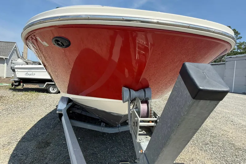 Slide: The Image of 2014 Sea Ray 240 Sundeck Outboard with red hull on trailer, parked outdoors. - 14
