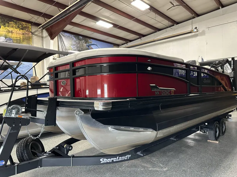 Slide: The Image of 2021 Barletta 23QCSS pontoon boat in showroom, red and black design, on trailer. - 5