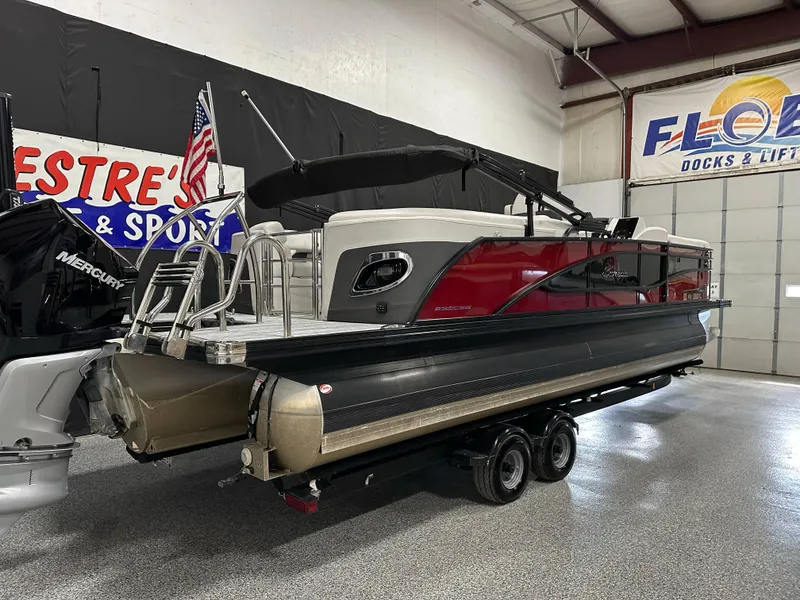Slide: The Image of 2021 Barletta 23QCSS pontoon boat in showroom, featuring red and black design with Mercury engine. - 8