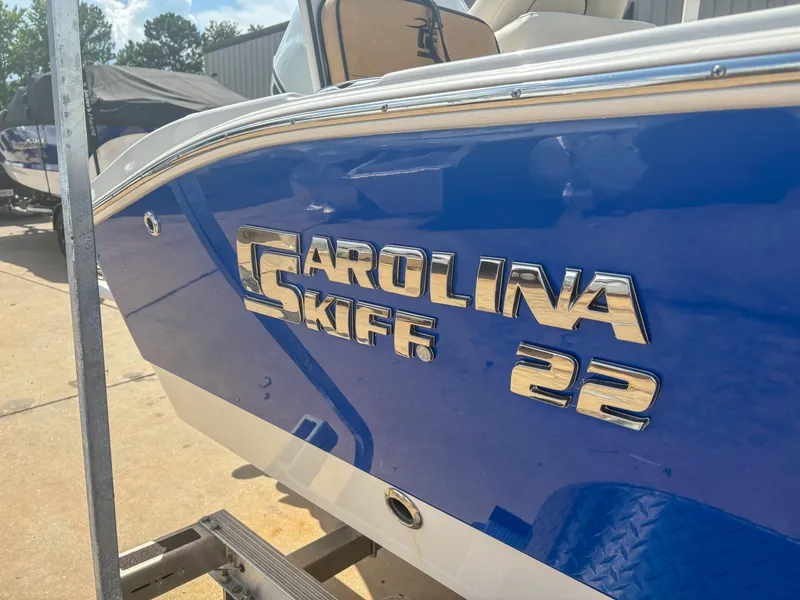Slide: The Image of 2024 Carolina Skiff 22 Ultra Elite boat with blue hull and chrome logo. - 4