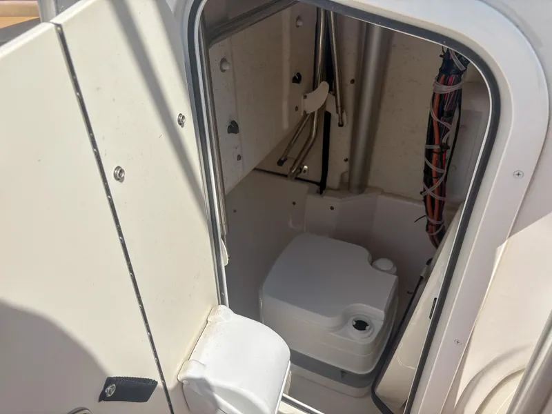 Slide: The Image of 2024 Carolina Skiff 22 Ultra Elite boat interior with compact toilet and wiring. - 9