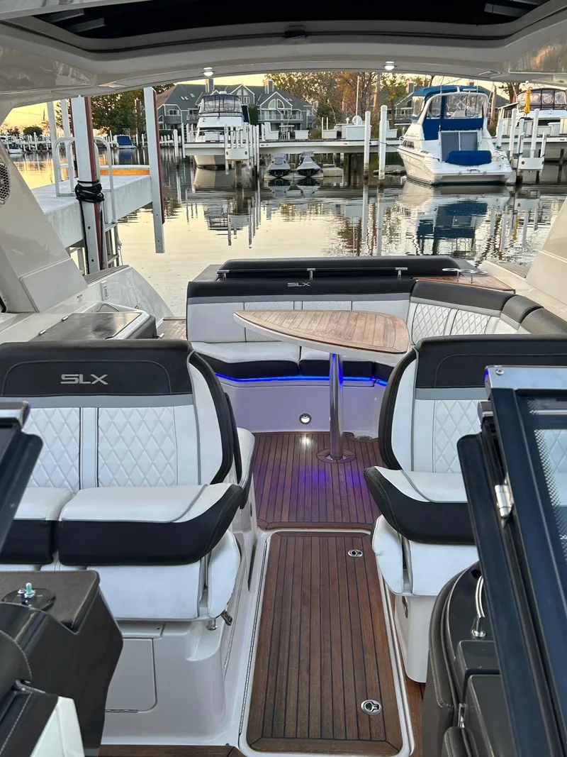 Slide: The Image of 2016 Sea Ray 310 SLX boat interior with luxurious seating and wooden flooring at a marina. - 7