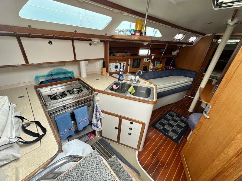 Slide: The Image of Interior of a 1999 Catalina 320 sailboat featuring a compact kitchen and seating area. - 12