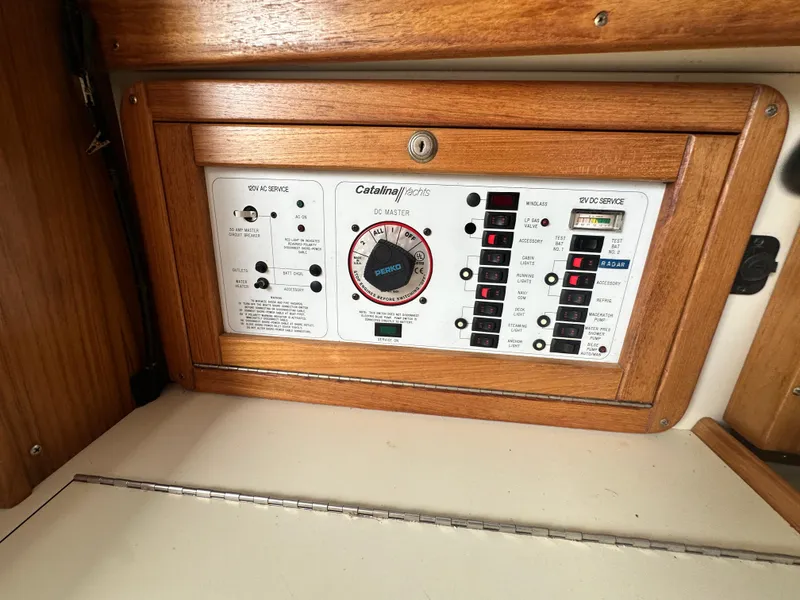 Slide: The Image of Control panel of a 1999 Catalina 320 yacht with wooden frame and various switches. - 15