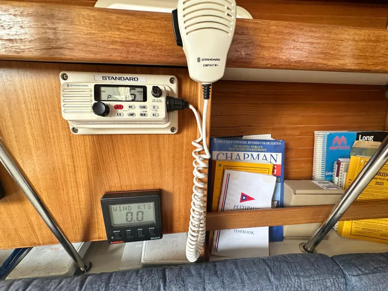 Slide: The Image of 1999 Catalina 320 interior with radio, wind gauge, and nautical books. - 17