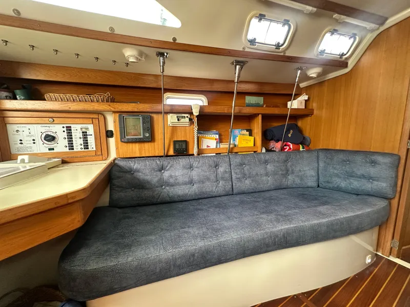 Slide: The Image of Interior of a 1999 Catalina 320 sailboat with a cozy blue sofa and navigation equipment. - 21