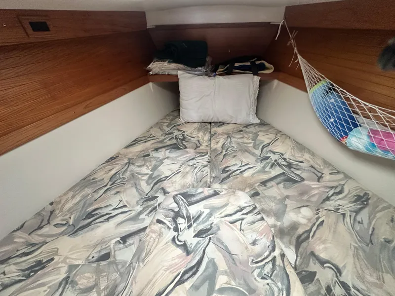 Slide: The Image of 1999 Catalina 320 sailboat cabin with patterned bedding and storage net. - 23