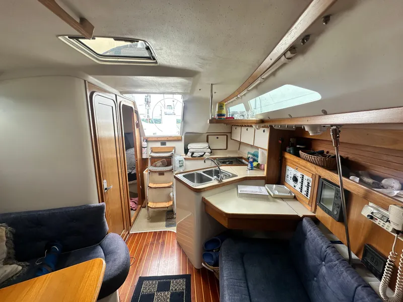 Slide: The Image of Interior of a 1999 Catalina 320 sailboat, featuring a cozy kitchen and seating area. - 24