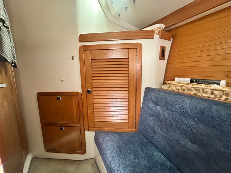 Slide: The Image of Interior of a 1999 Catalina 320 sailboat with wooden cabinets and blue seating. - 26
