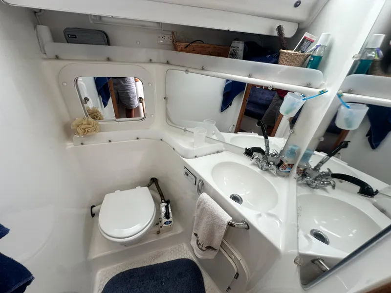 Slide: The Image of Bathroom interior of a 1999 Catalina 320 yacht, featuring a toilet and dual sinks. - 27