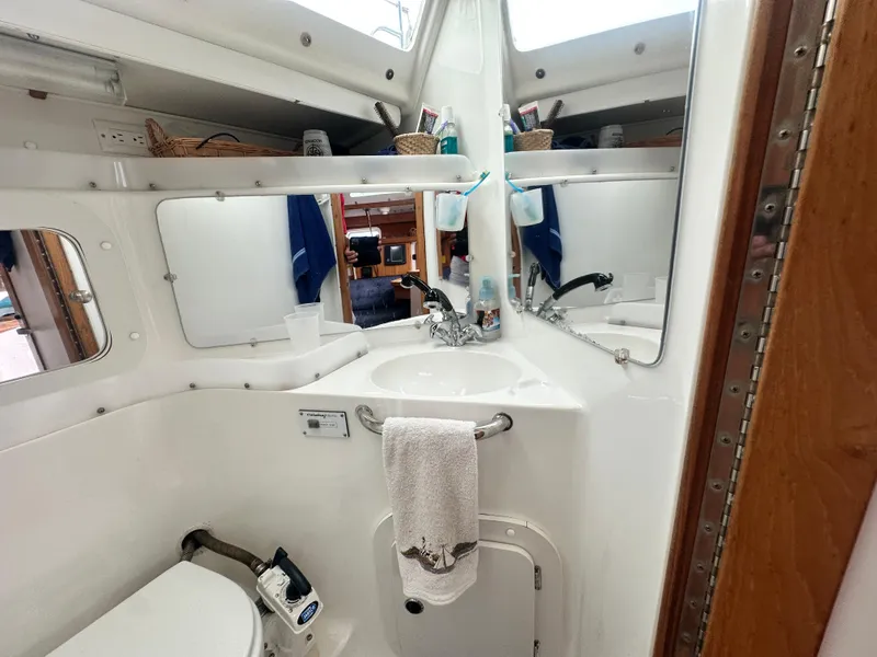 Slide: The Image of Bathroom interior of a 1999 Catalina 320 sailboat, featuring sink and mirror. - 28