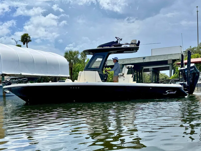The Image of 2026 Scout 281 XSS boat on water, under cloudy sky, with person at helm. - 0