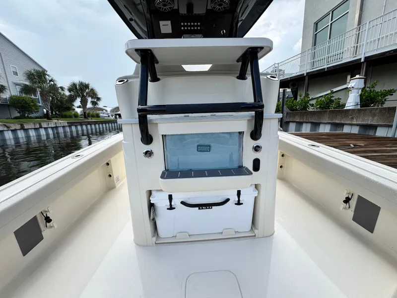 Slide: The Image of 2026 Scout 281 XSS boat interior with storage and cooler, docked by waterfront homes. - 12