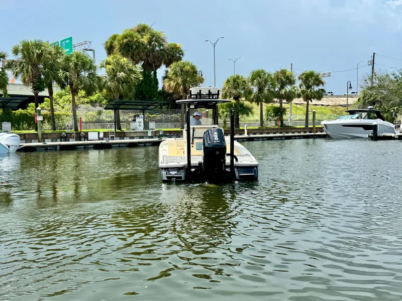 Slide: The Image of 2026 Scout 281 XSS boat docked on a calm waterway with palm trees in the background. - 2