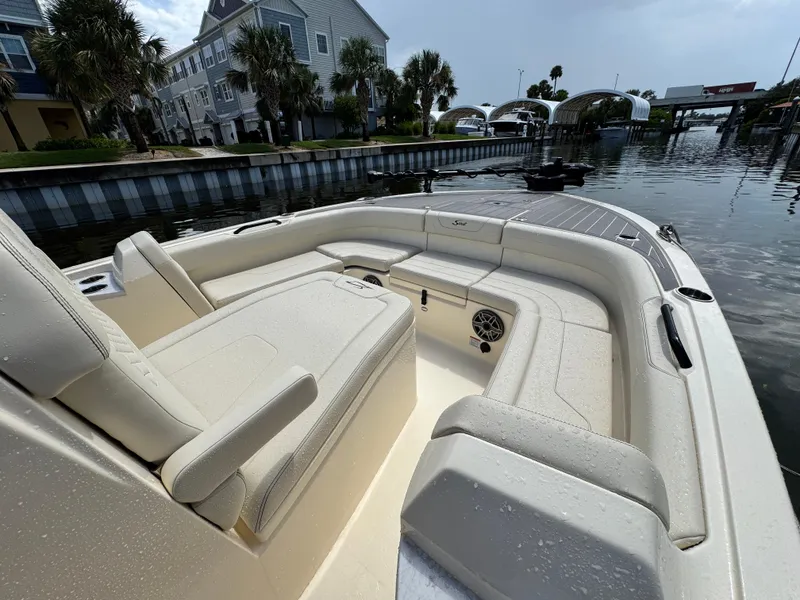 Slide: The Image of 2026 Scout 281 XSS boat interior with beige seating, docked near waterfront homes. - 21