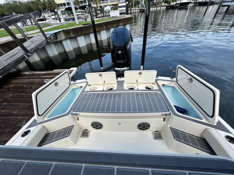 Slide: The Image of 2026 Scout 281 XSS boat at dock, open storage compartments, and visible outboard motor. - 8