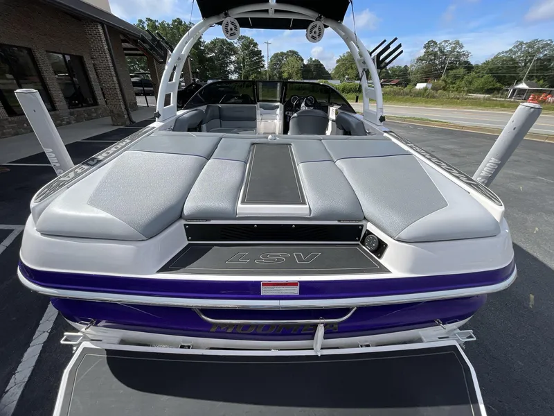 Slide: The Image of 2015 Moomba Mobius LSV boat with gray seating and purple accents, parked outdoors. - 12